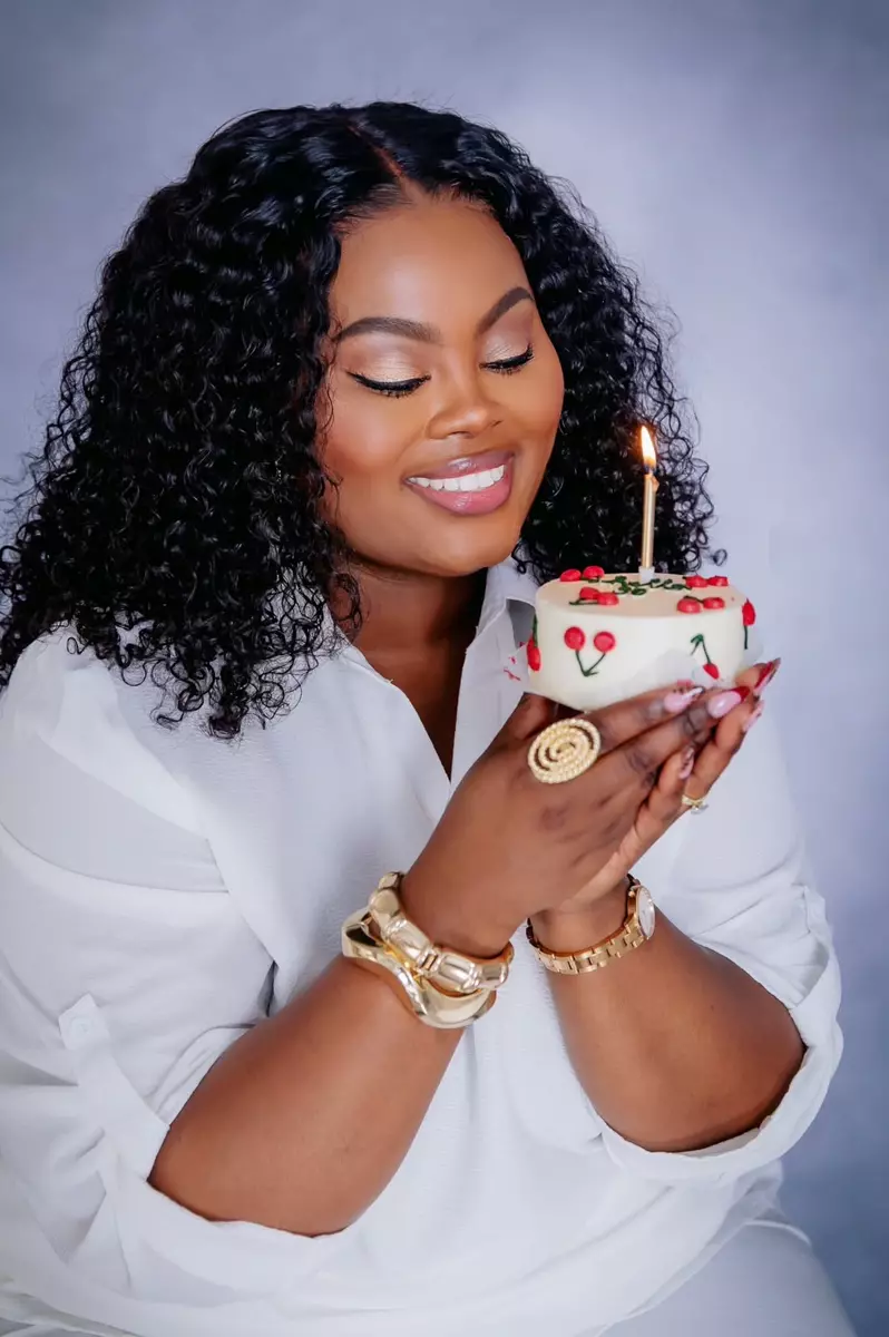A woman holding a small birthday cake with a lit candle