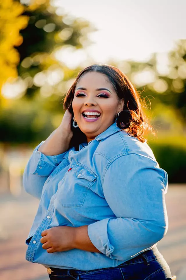A smiling woman wearing a denim shirt