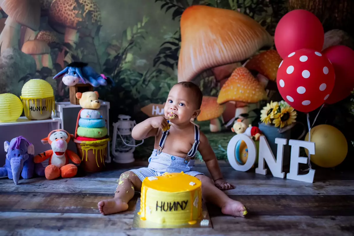 First birthday cake smash photoshoot of a baby boy with Winnie the Pooh theme