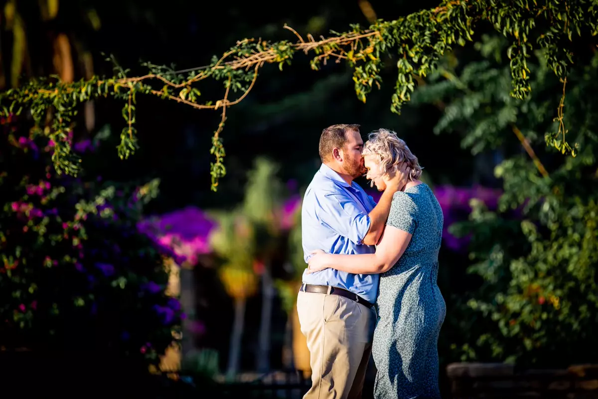 A couple embracing in a garden with warm sunlight highlighting them