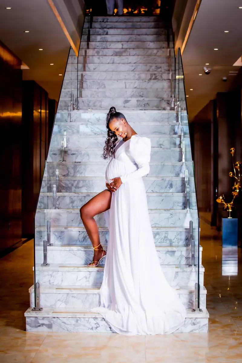 Pregnant woman in a white dress standing on a grand marble staircase