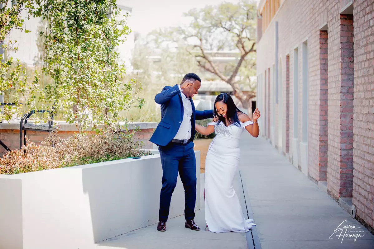 A couple playfully dancing on an outdoor walkway