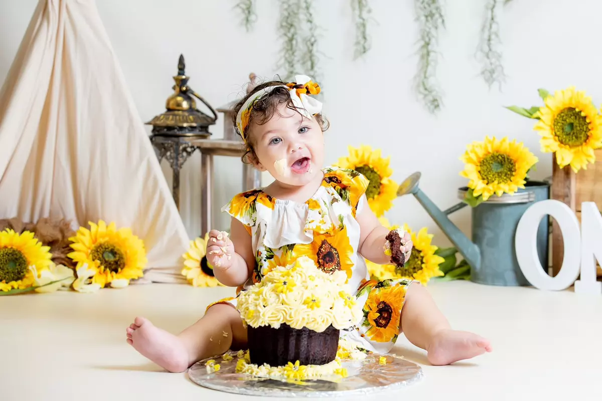 Baby girl eating a cupcake with sunflower theme