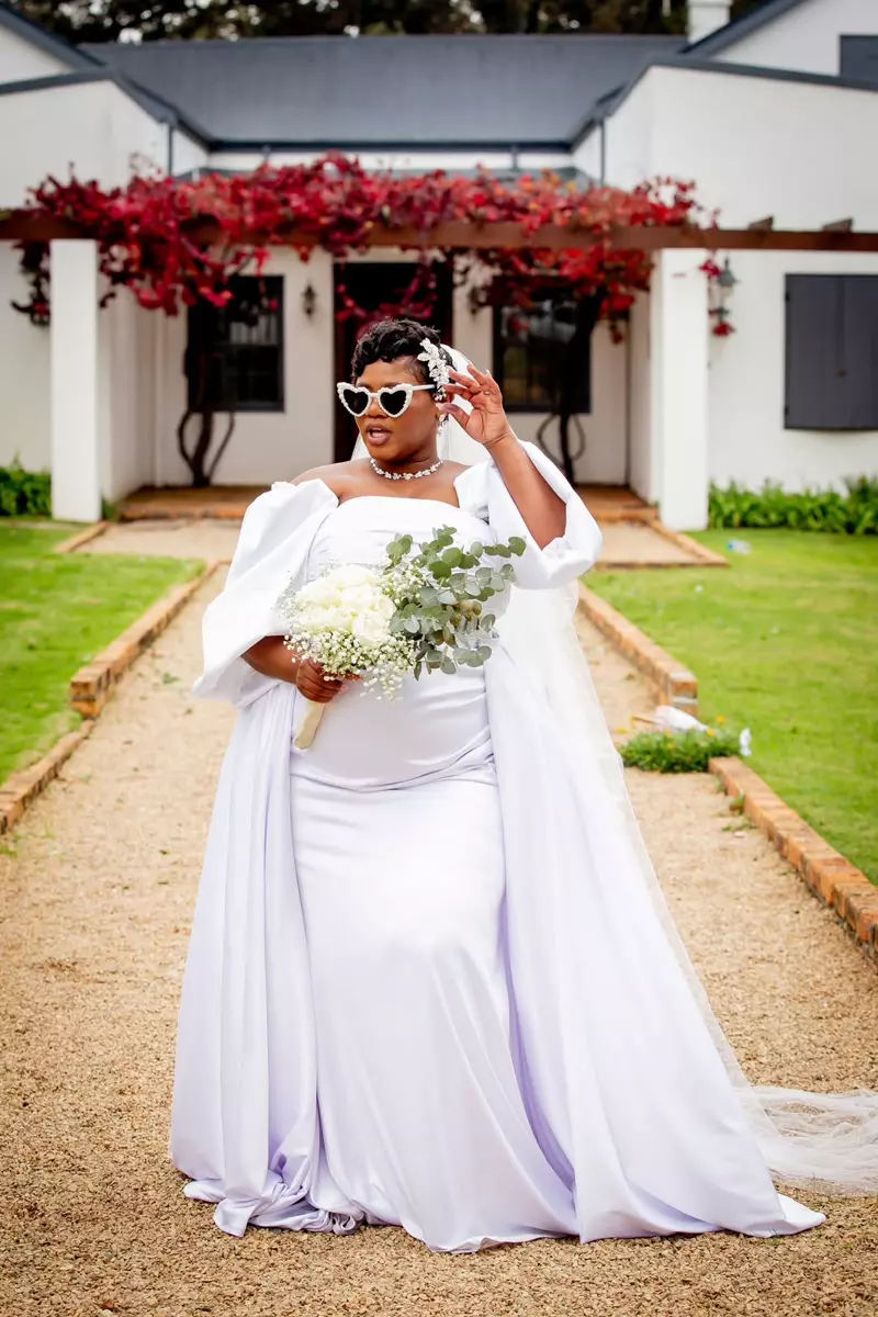 A stylish bride wearing heart-shaped sunglasses and a white wedding gown
