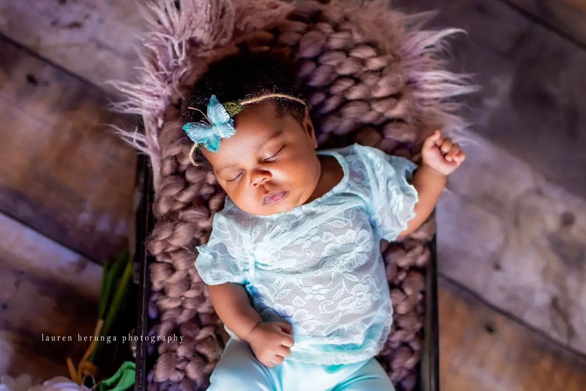 Sleeping newborn baby in a basket on a wooden floor