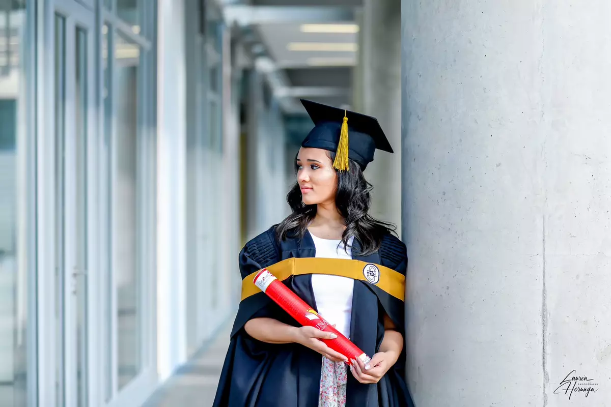 Graduate student in gown and cap holding a diploma