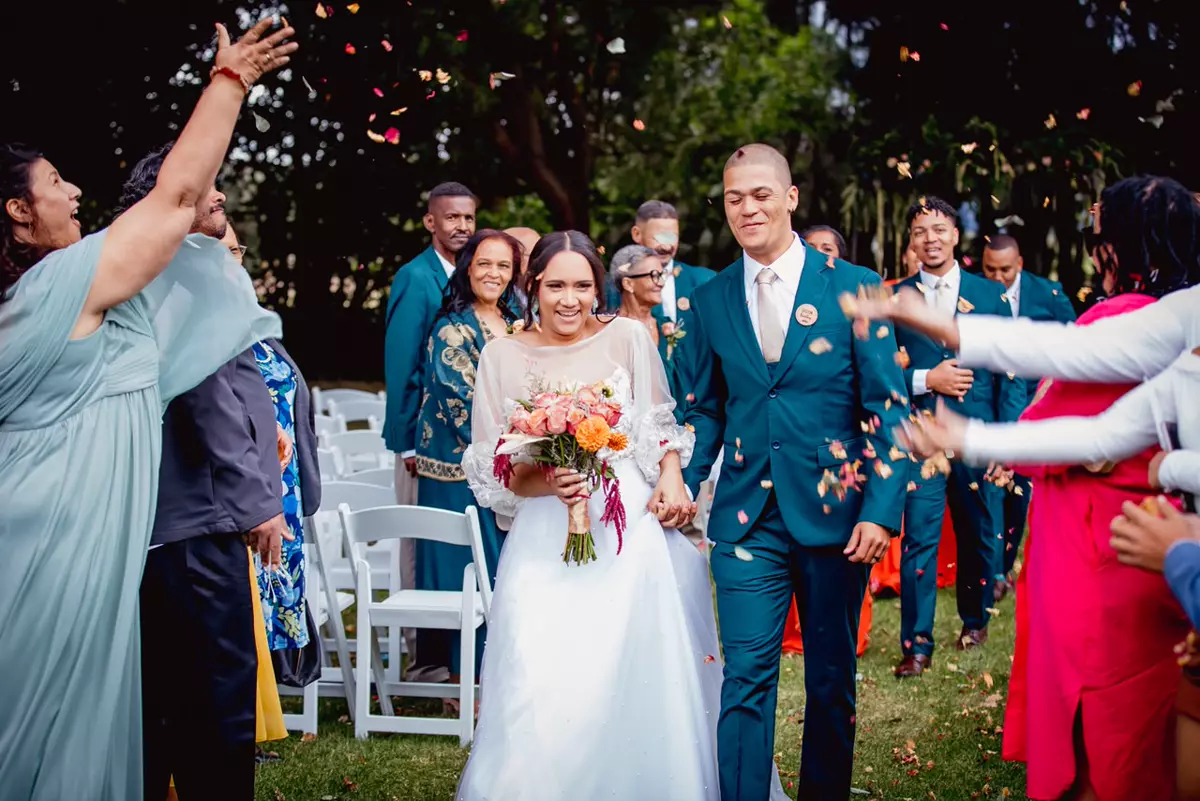 Bride and groom walking down the aisle after their wedding ceremony, surrounded by guests throwing confetti