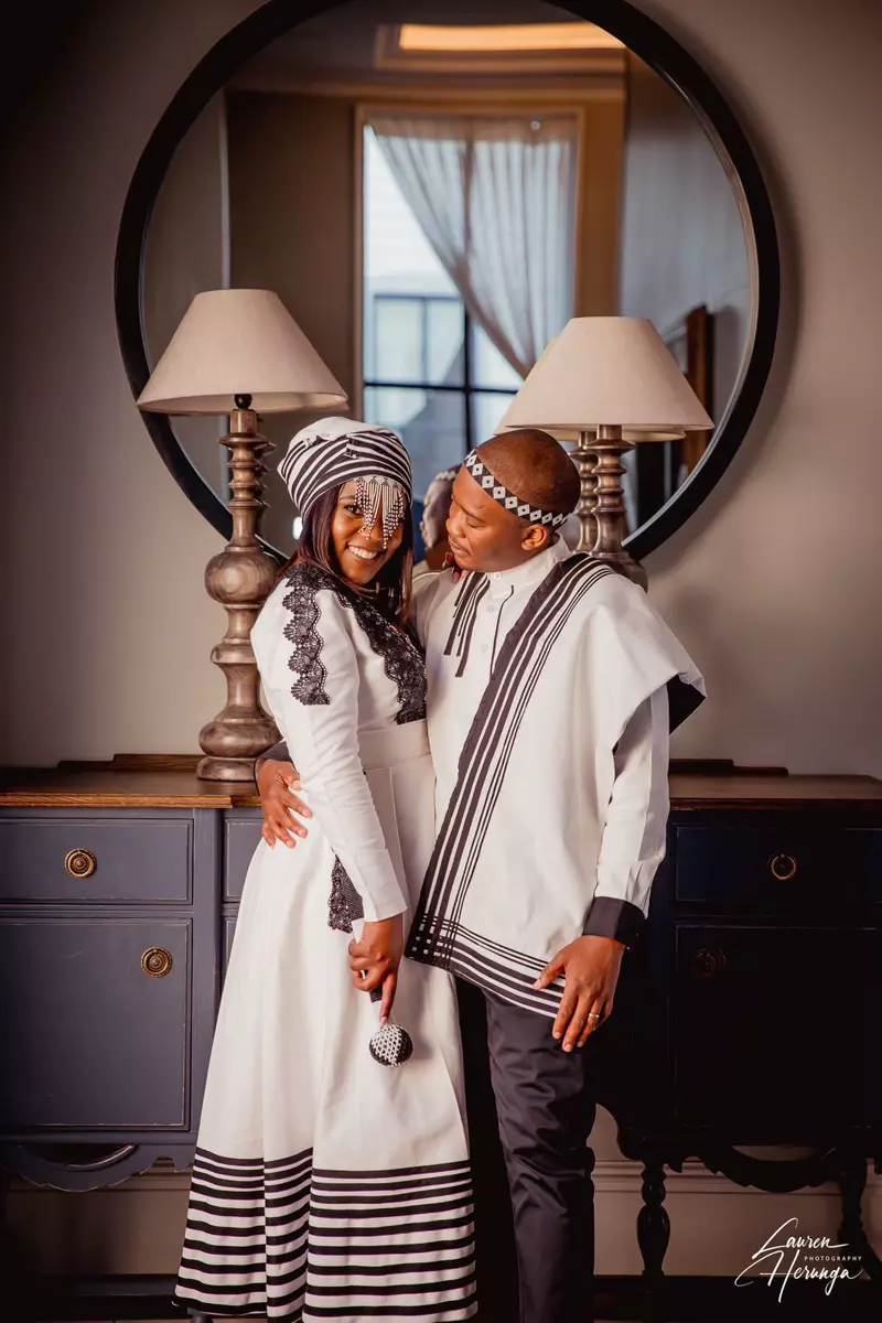 A couple dressed in traditional African attire posing indoors