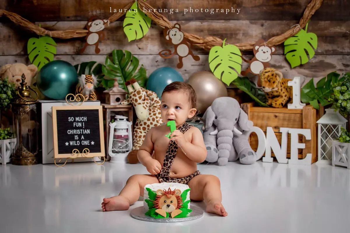 Baby boy sitting in front of a smash cake with jungle-themed decorations