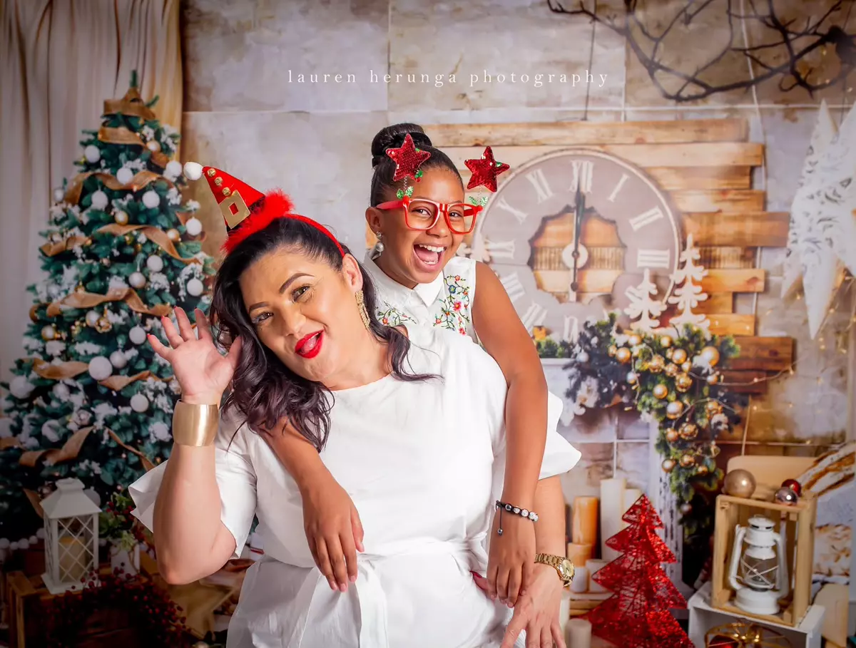 A woman and a young girl posing together in a Christmas-themed photo studio