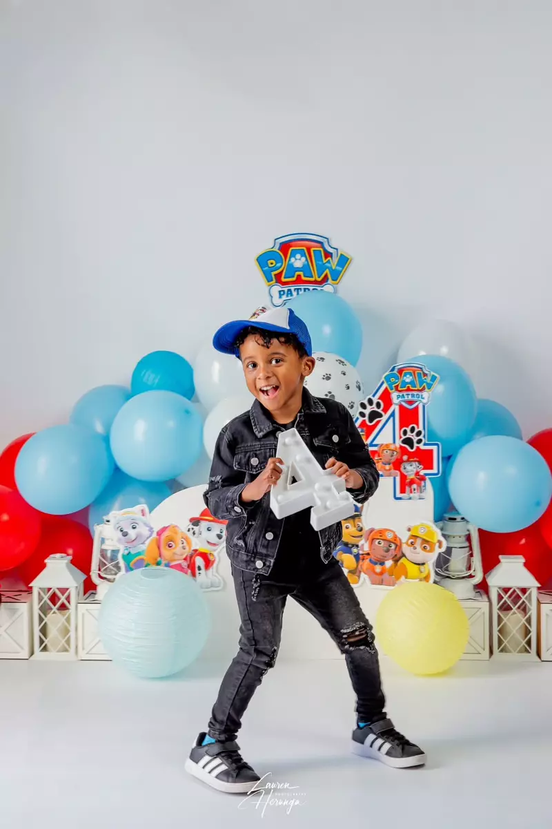 A young boy celebrating his 4th birthday with a Paw Patrol themed party setup