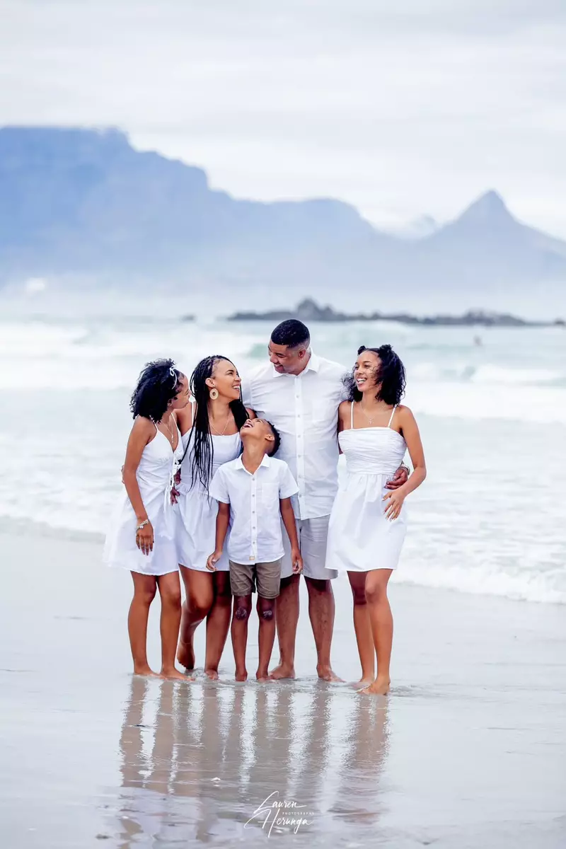 Family standing together in shallow water with mountains in background