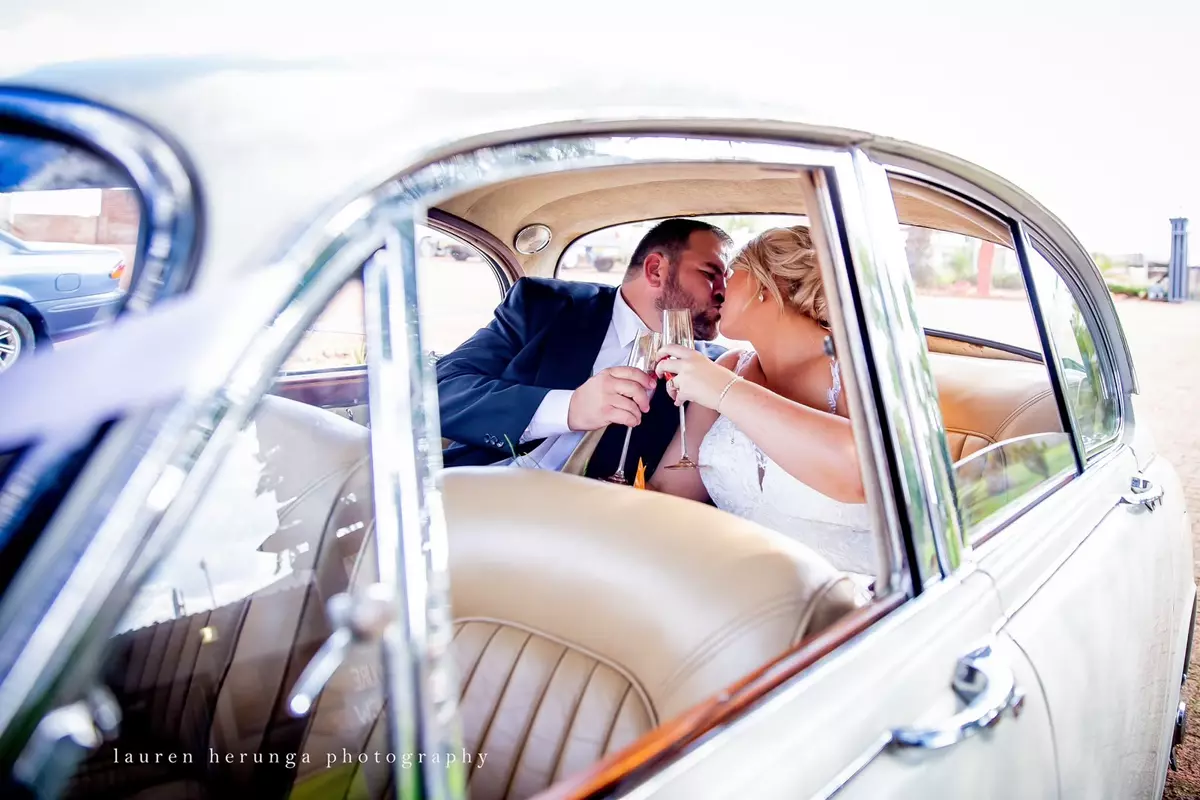Bride and groom kissing in a vintage car