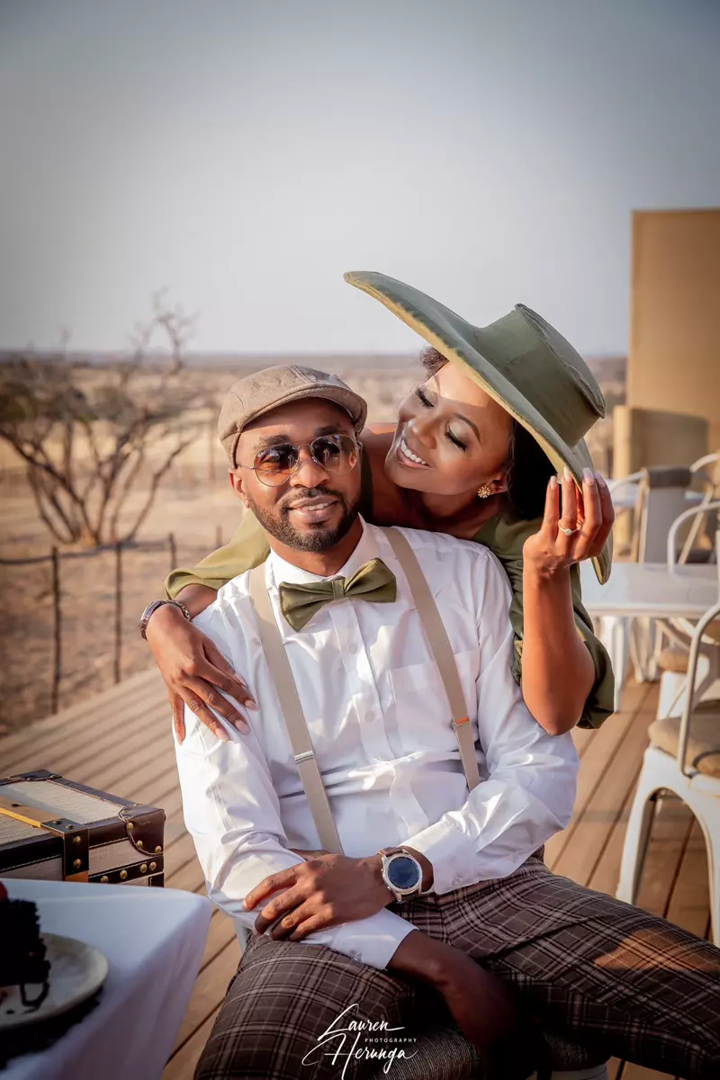 A couple posing outdoors on a wooden deck in safari-style attire