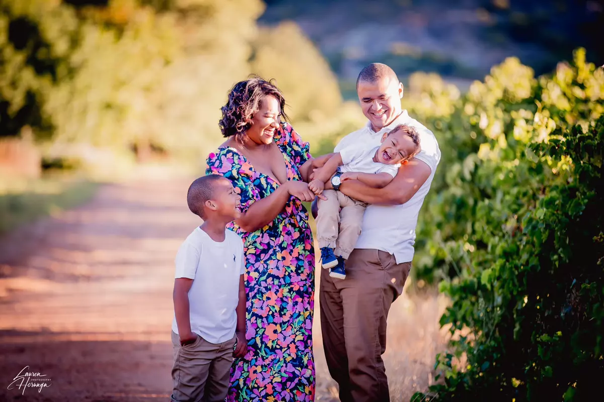 Family of four outdoors in a vineyard, laughing and smiling