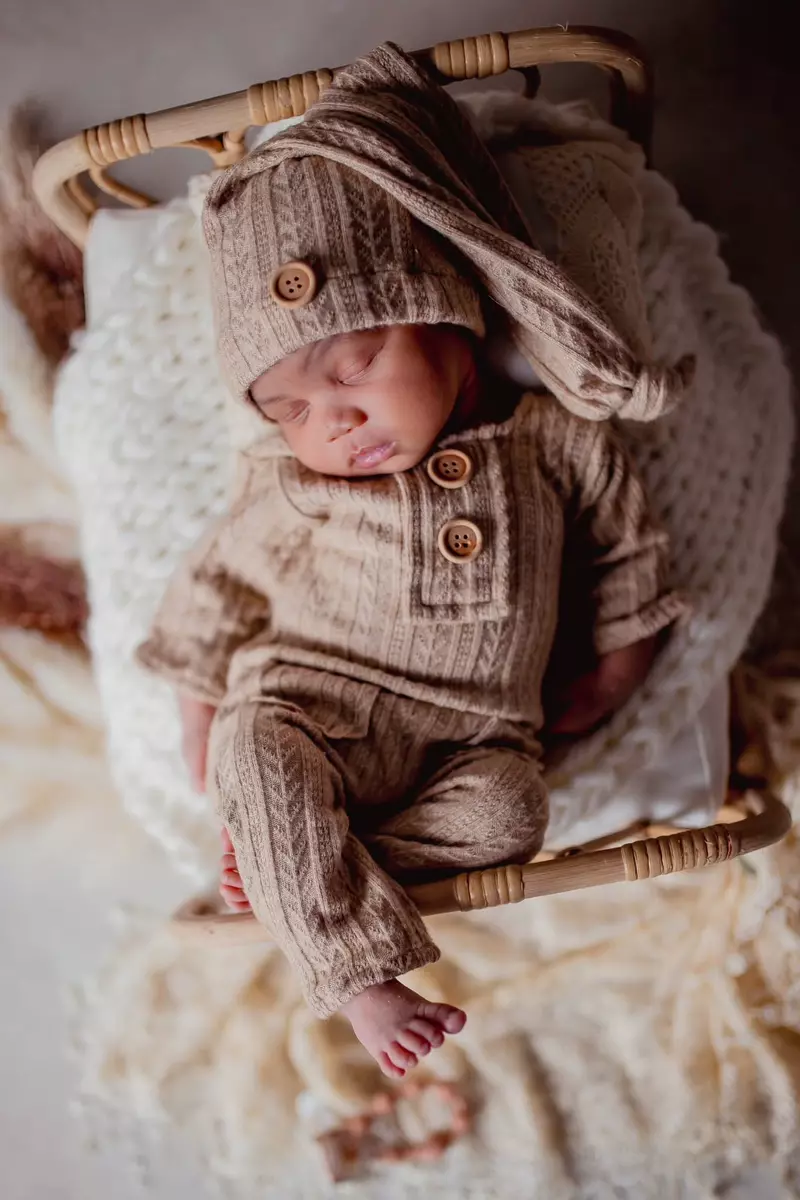 Sleeping newborn baby in a matching knit set and hat