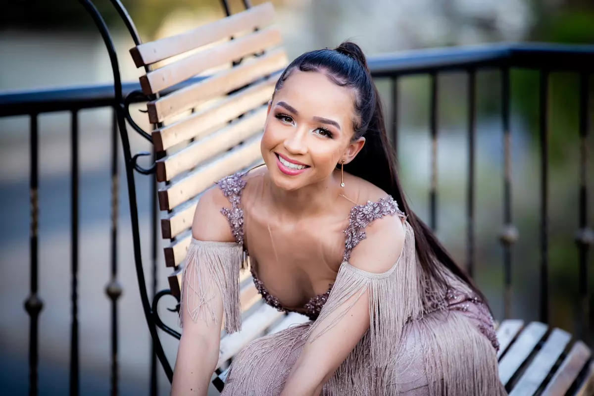 A young woman smiling while posing on a bench outdoors