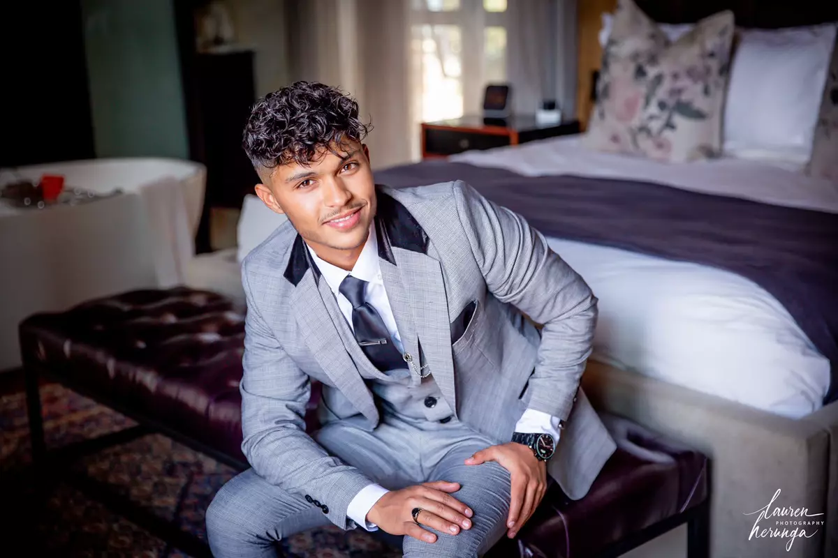 A young man in a grey suit sitting on a leather bench
